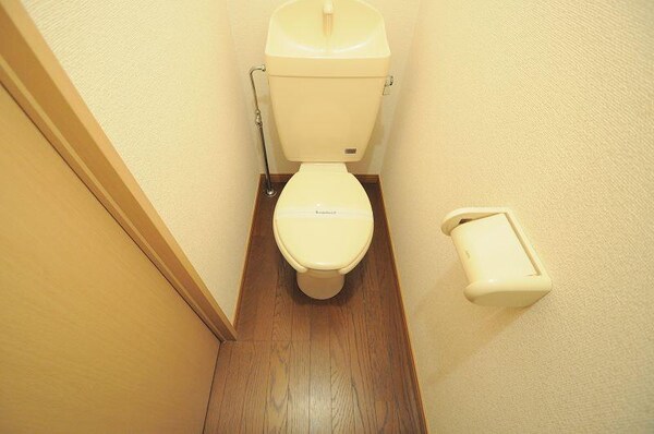 トイレ(木の扉・床と調和した壁紙を採用し、落ち着いた空間を演出)